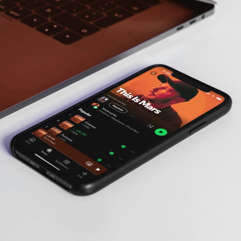 A smarphone on a white table. The screen shows spotify open on This Is Mars' artist profile.
