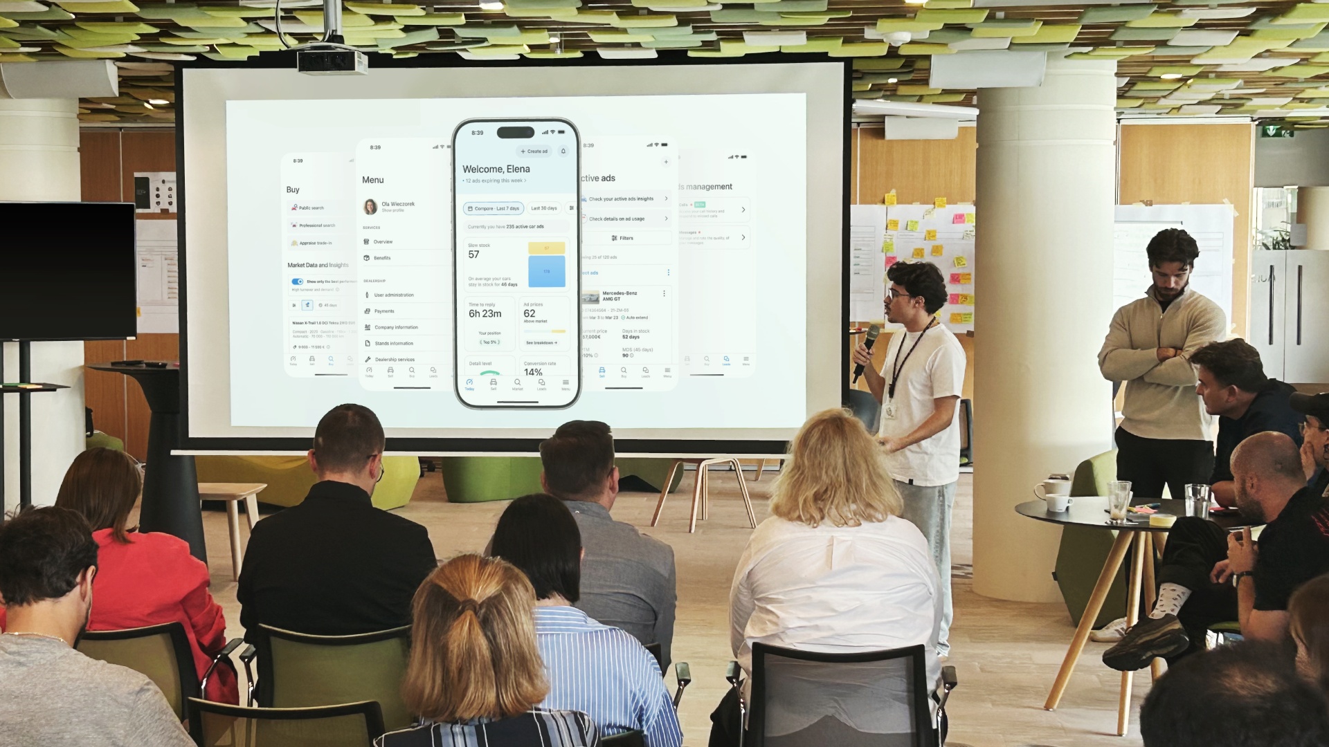 A designer presenting images of an app to an audience in a large conference room.