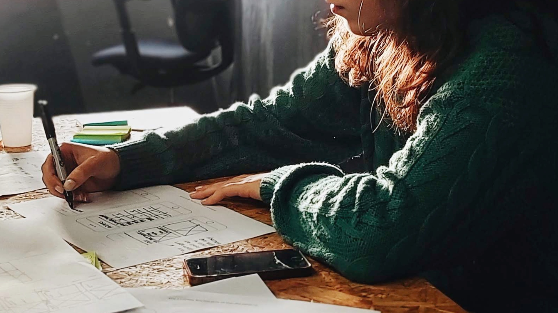 A woman drawing an app sketch with pen and paper.